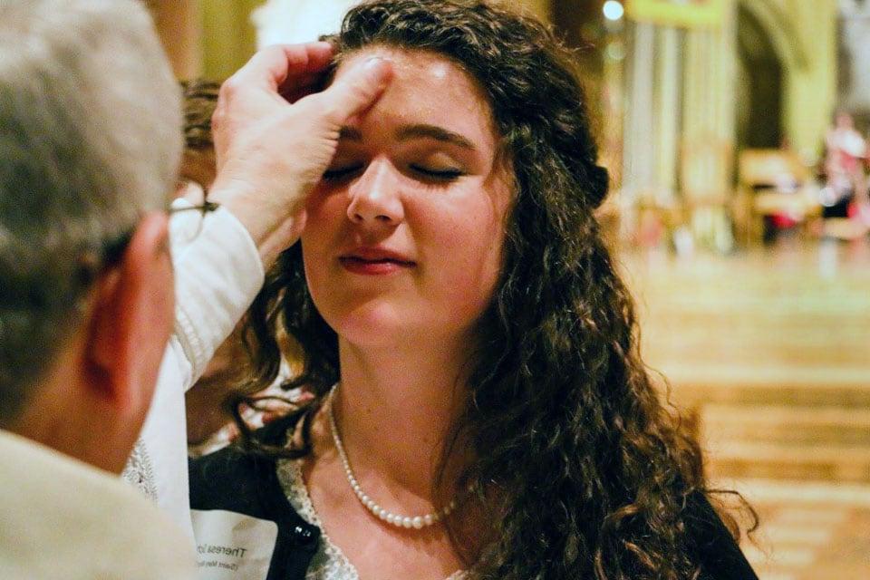 A Mass participant receives ashes on her forehead from a priest.